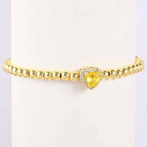 Detail of gold heart charm with yellow zircon and pavé crystals on a beaded bracelet