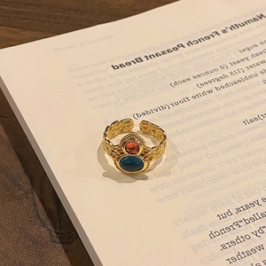 Close-up of vintage gold ring with blue and orange gems on a book page