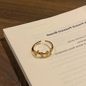 Close-up of a gold leaf ring with crystal inlay placed on a book page for a refined look