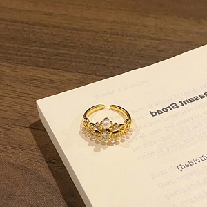 Detail of elegant gold crown ring with white pearls on a vintage book page