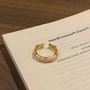 Detailed macro view of an adjustable gold ring with pink enamel and diamond-set floral studs