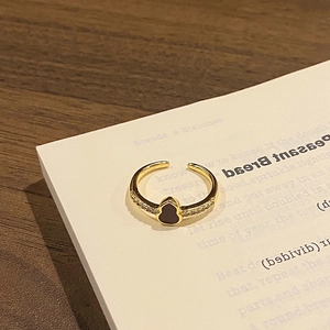 Macro detail of a gold open ring featuring a black hulu gourd charm and zircon side stones