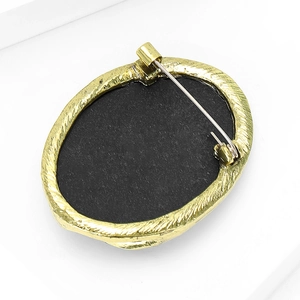 Vintage gold relief brooch back view showing silver safety pin and detailed engraving