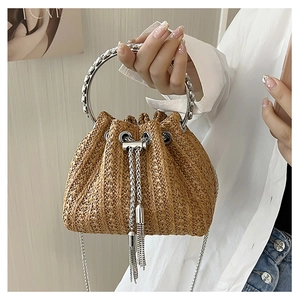Detail of straw bucket bag with silver metal ring handle and fringe tassel drawstring