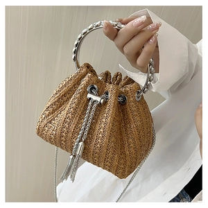 Detail of straw bucket bag with silver ring handle, beaded decor, and metal tassels