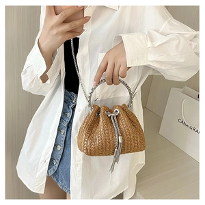 Detail of woven straw bucket bag with silver metal ring handle and fringe accents