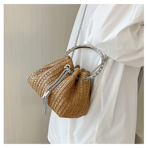 Detail of straw bucket bag with silver chain tassels and round metal handle