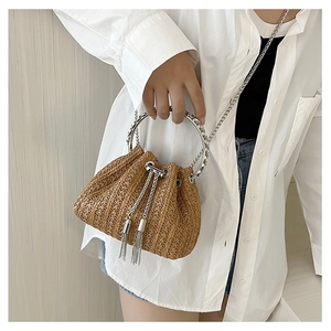 Detail of straw bucket bag with silver metal ring handle and fringe tassel accents
