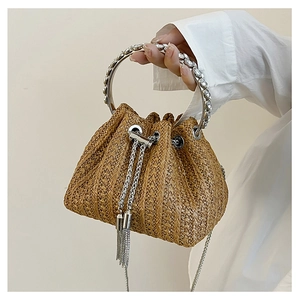 Detail of straw bucket bag with rhinestone metal handle and silver chain tassels