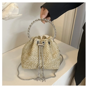 Macro shot of a straw bucket bag with silver metal ring handle and tassel drawstring detail