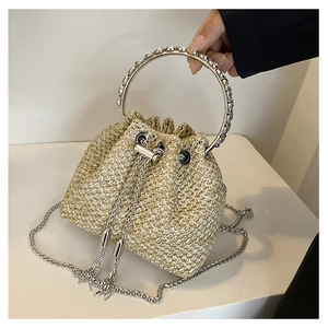Detailed close-up of straw bucket bag with silver ring handle and metal tassel charm
