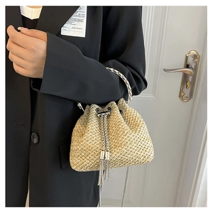 Detailed shot of gold straw bucket bag with silver tassels and round metal handle