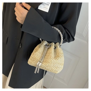 Detail of straw bucket bag with silver tassel drawstring and metal ring handle