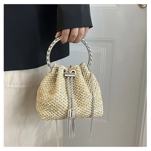 Detail of straw bucket bag with silver metal ring handle, tassel, and chain strap