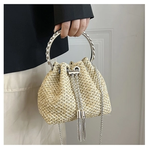 Close-up of straw bucket bag with silver metal handle and rhinestone chain detail