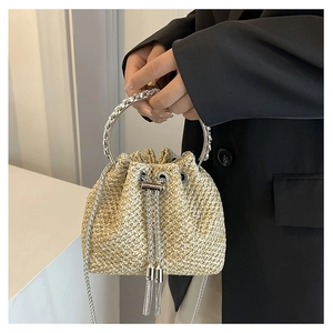 Detail of straw bucket bag with metal drawstring closure and chic tassel accents
