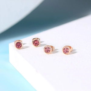 Detailed view of four round pink zircon stud earrings with rose gold plating on a stand