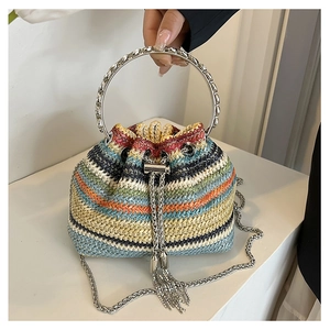 Detail of colorful woven straw bucket bag with metal handle and tassel fringe decoration