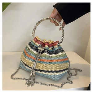 Detail of colorful striped straw bucket bag with metal handle and fringe tassels