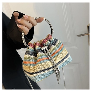 Detail of colorful woven straw bucket bag with silver metal ring handle and tassels