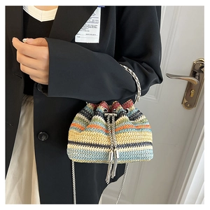 Detail of colorful woven straw bucket bag with silver metal ring handle and striped pattern