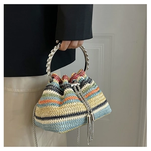 Close-up of colorful striped straw bucket bag with silver metal handle and tassel