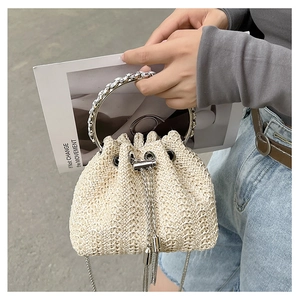 Detail of woven straw bucket bag with rhinestone-encrusted round metal handle and drawstring