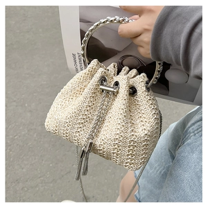 Close-up of woven bucket bag featuring rhinestone metal handles and chain drawstring