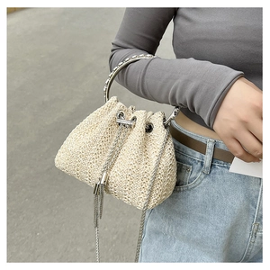 Detail of straw bucket bag with silver ring handle and chain strap on a model