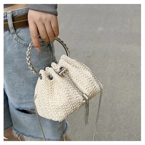 Detail of woven straw bucket bag with rhinestone-encrusted silver circular handles