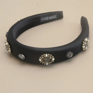 Elegant black satin headband with grey crystals and pearls on beige background