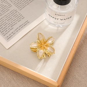 Detail of bohemian gold flower hair claw with yellow pearlescent enamel finish