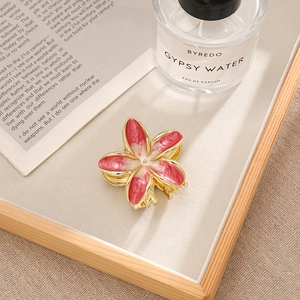 Detailed close-up of bohemian floral hair claw clip with red marble finish on gold metal