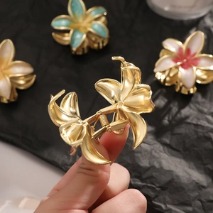 Golden bohemian frangipani hair claw clip with enamel petals shown in close-up view