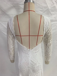 Detail of white lace long sleeve dress featuring an open back V-neck and delicate textures