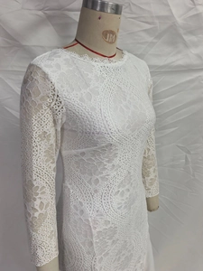 Detail of white lace dress showing intricate scroll patterns and eyelash lace neckline
