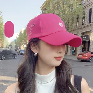 Outdoor shot of a rose pink corduroy bucket hat featuring embroidered heart and script