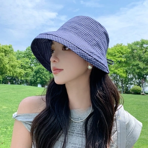 Detail of dark blue plaid sun hat with a side bow accent worn in an outdoor setting
