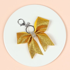 Close-up of sparkling gold glitter bow keychain with rhinestones and metal lobster clasp