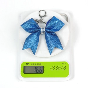 Blue glitter bow keychain with rhinestones and silver hardware on a digital scale