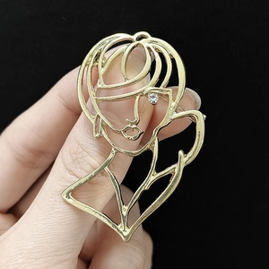 Macro view of gold hollow-out female silhouette brooch with a sparkling white rhinestone eye