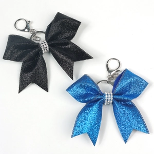 Close-up of glitter bow keychains in black and blue with sparkling rhinestone centers