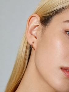 Macro shot of 7mm gold sterling silver huggie hoop earring with pink cubic zirconia stones
