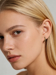 Detail of 7mm gold huggie earrings featuring micro-pave set sparkling black cubic zirconia