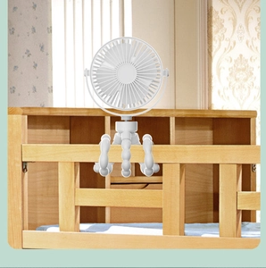 Octopus fan with flexible tripod legs wrapped around a wooden crib fence for baby
