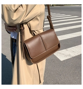 Detail of vintage dark brown crossbody bag with stitch accents in a street style setting