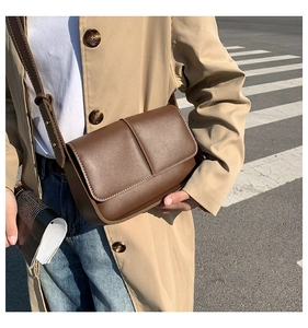 Detail of vintage brown shoulder bag with textured finish and adjustable strap on a model