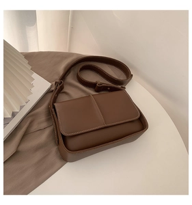 Close-up of vintage brown leather crossbody bag with detailed white stitching and strap
