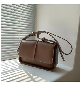 Detail of vintage brown leather crossbody bag featuring white contrast stitching and soft light