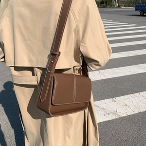 Retro brown leather crossbody square bag with adjustable rivet strap worn on beige coat